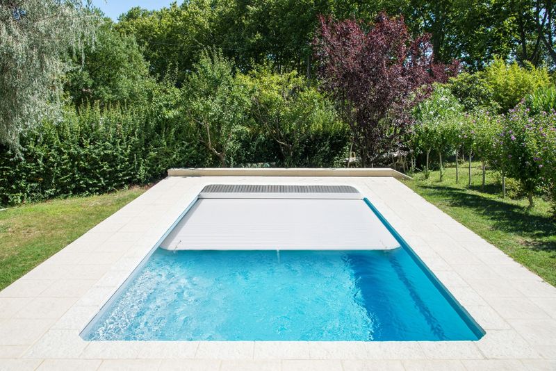 Piscines coque polyester avec rideau automatique immergée et caillebotis bois