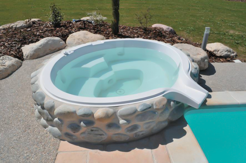 Spa à débordement installé près d'une piscine en polyester